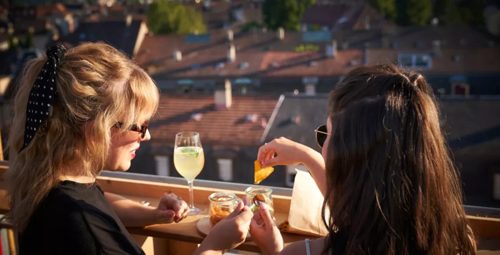 Zwei Frauen beim Apero auf einer Dachterrasse im Abendlicht.