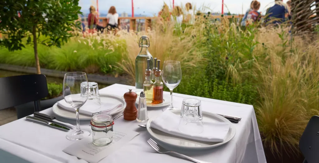 Gedeckter Tisch mit weissem Tischtuch auf einer Dachterrasse.