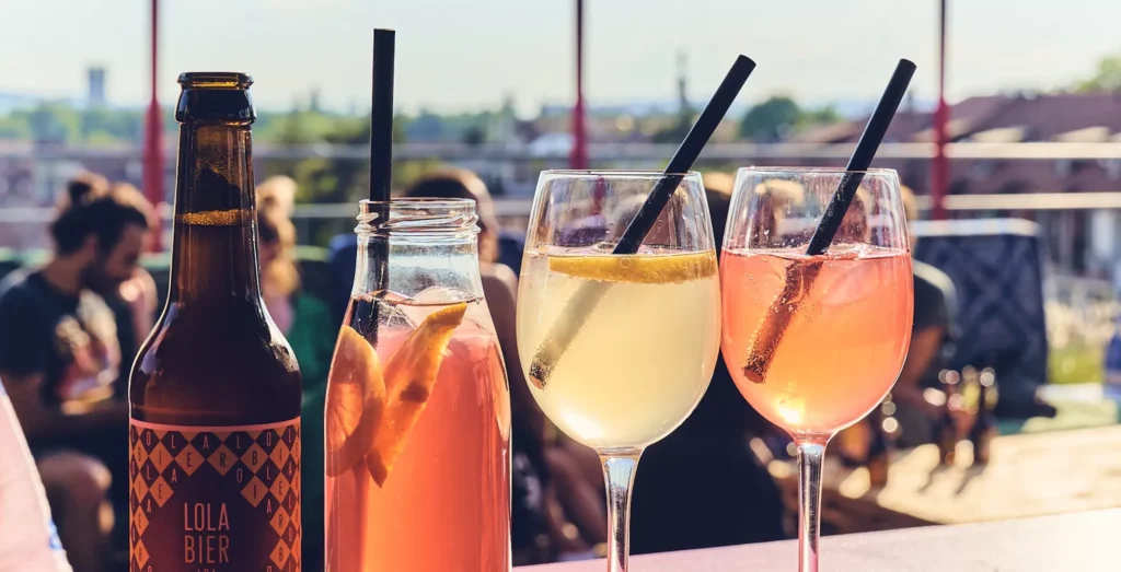 Ein Bier und drei Drinks mit Strohhalmen auf einer Bar.