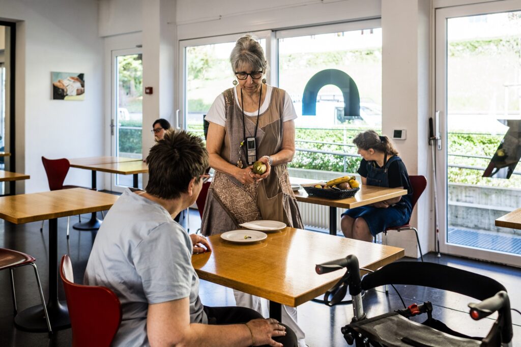 Pflegerin die vor einem Tisch steht. 