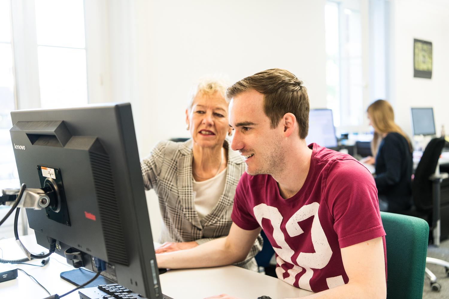 Zwei Personen vor einem Computer die zusammen etwas anschauen.