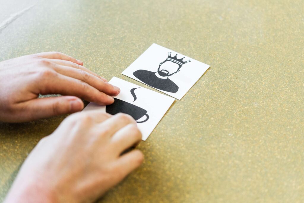 Zwei Hände mit zwei Karten mit Symbolen auf einem Tisch.