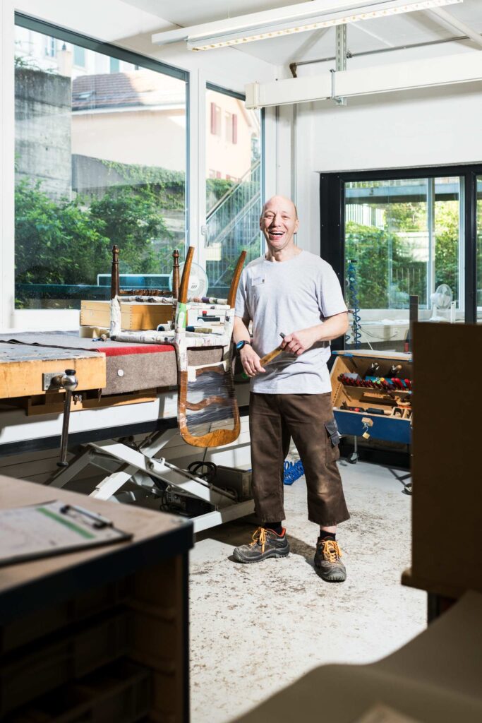 Bild zeigt, ein Mitarbeiter vom B der in der Werkstatt der Sesselflechterei arbeitet.