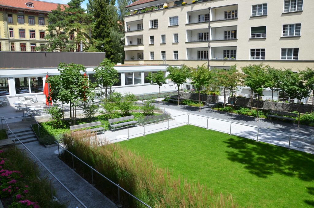 Gepflegter Garten mit grüner Wiesse in einem Innenhof. 