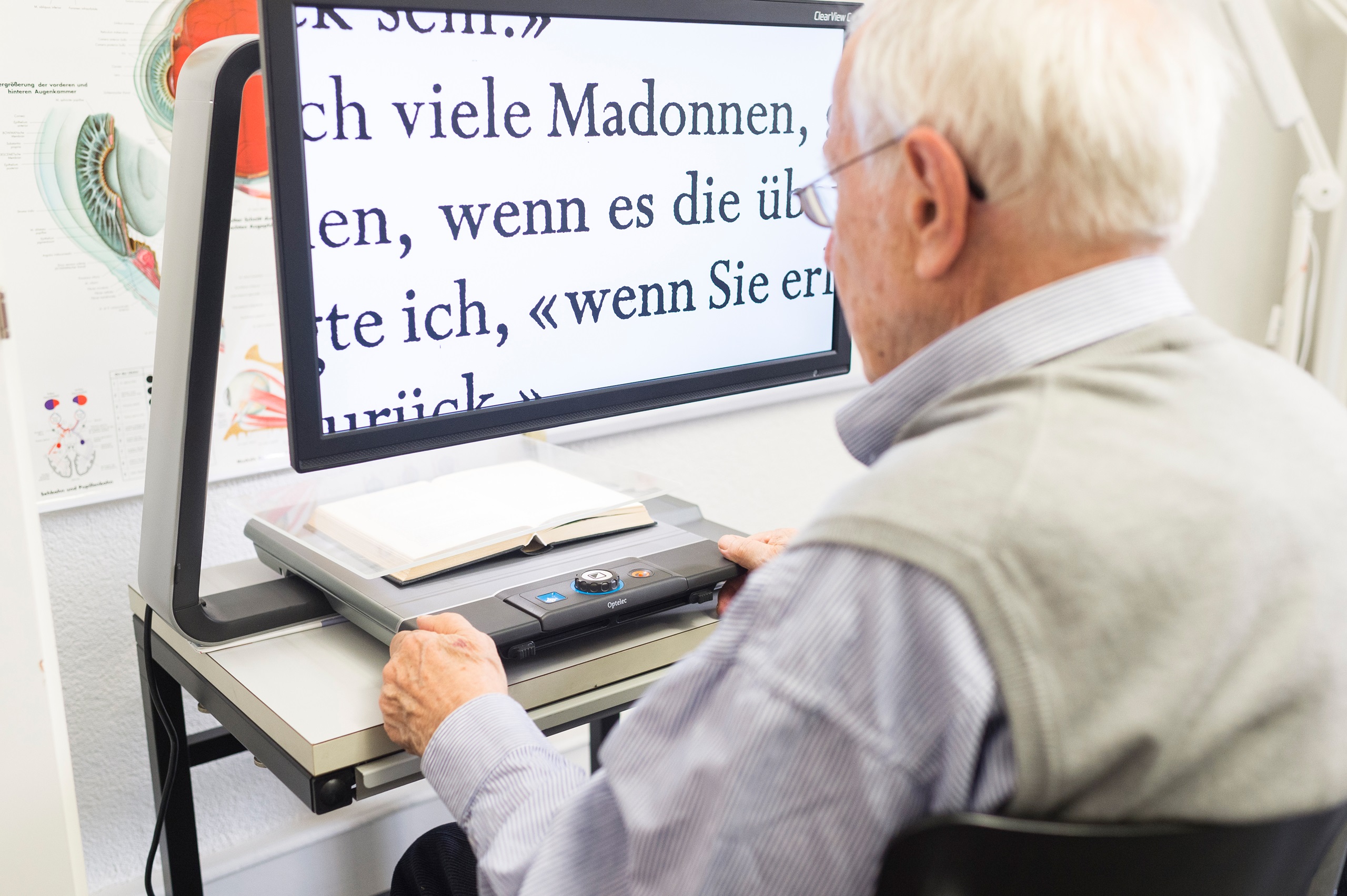 Bild zeigt einen älteren Mann der über ein Bildschirmlesegerät ein Buch liest.