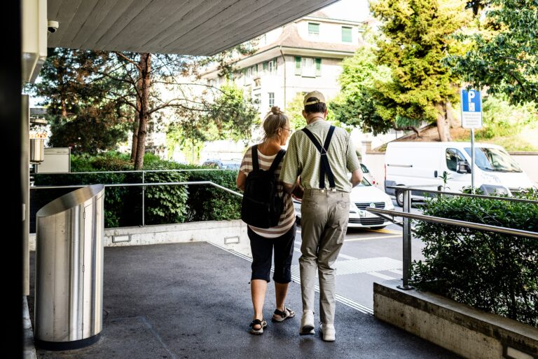 Person die von einer Betreuerin nach draussen begleitet wird.
