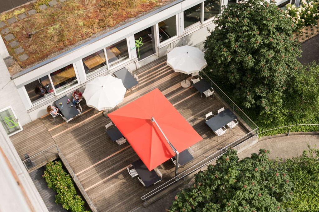 Aussenaufnahme einer Terrasse mit einem roten Sonnenschirm von oben.