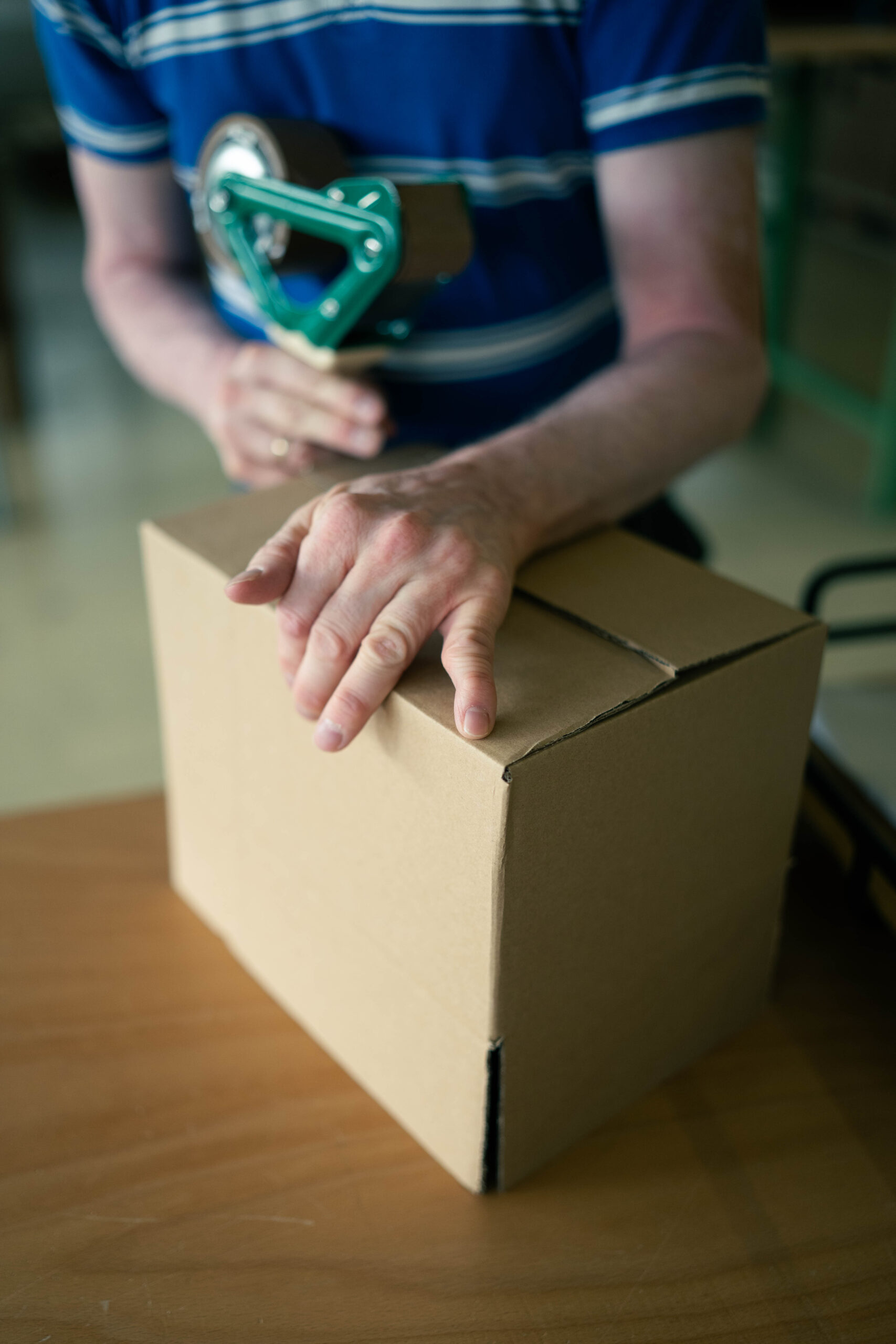 Ein Mitarbeiter klebt ein Paket zu.