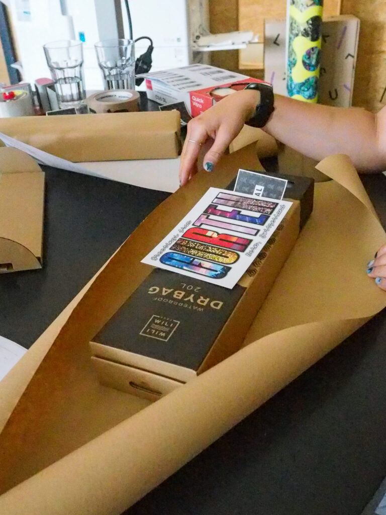 Ein Päcklein mit einem Drybag vom Grutenfestival und einer Postkarte wird verpackt