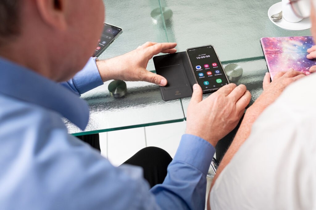 Peerberatung - ein blinder Mann schult eine sehbeeinträchtigte Person in der Nutzung eines Smartphones